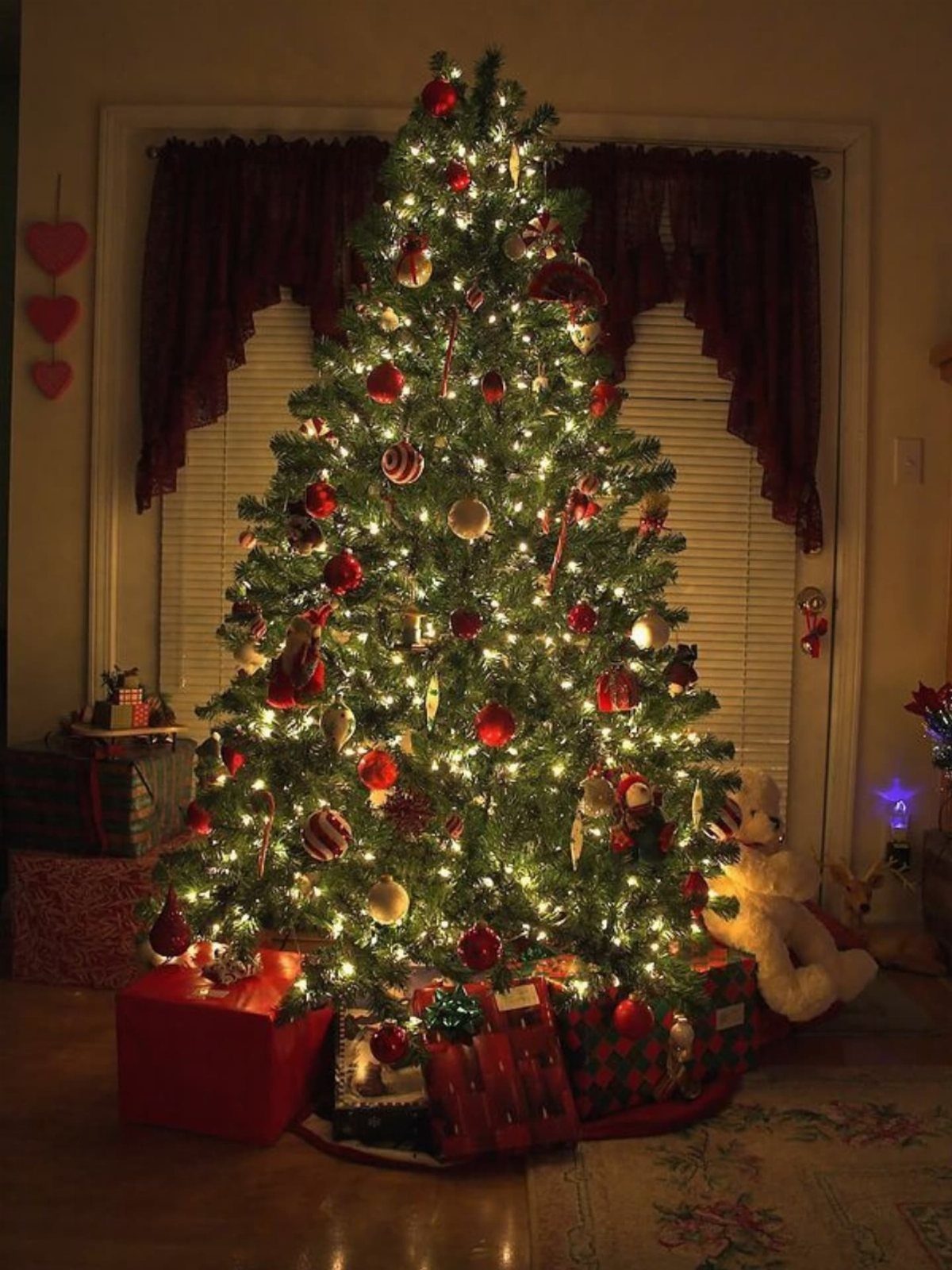 Christmas tree decorated with red and gold ornaments and warm white fairy lights.