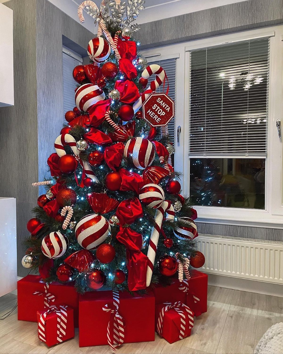 Christmas tree decorated with red and white striped ornaments and red ribbons.