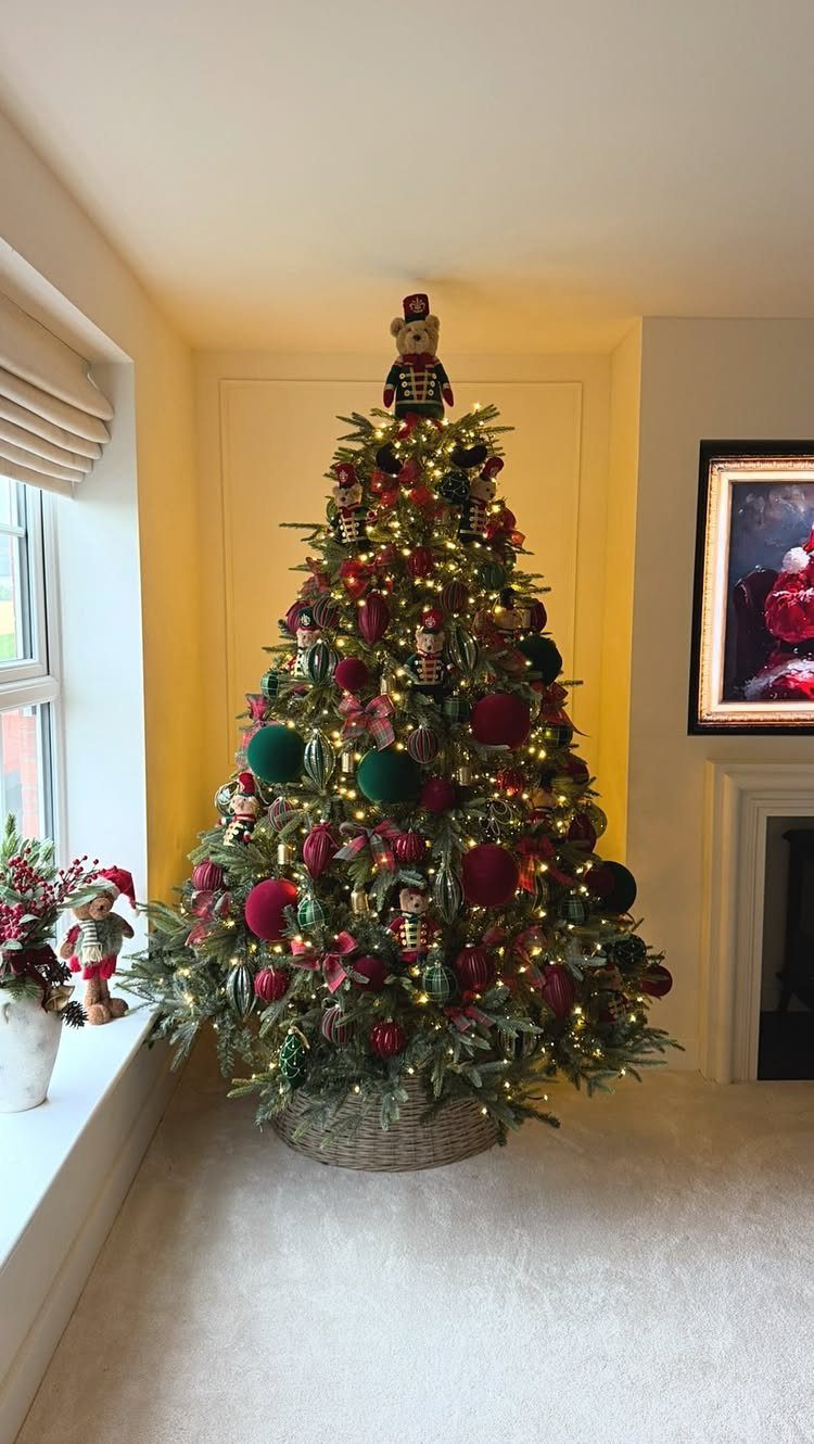 Decorated Christmas tree with red and green ornaments and a nutcracker on top.
