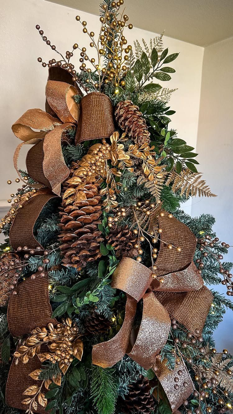 Christmas tree decorated with brown glitter ribbons, large pinecones, and gold metallic accents.