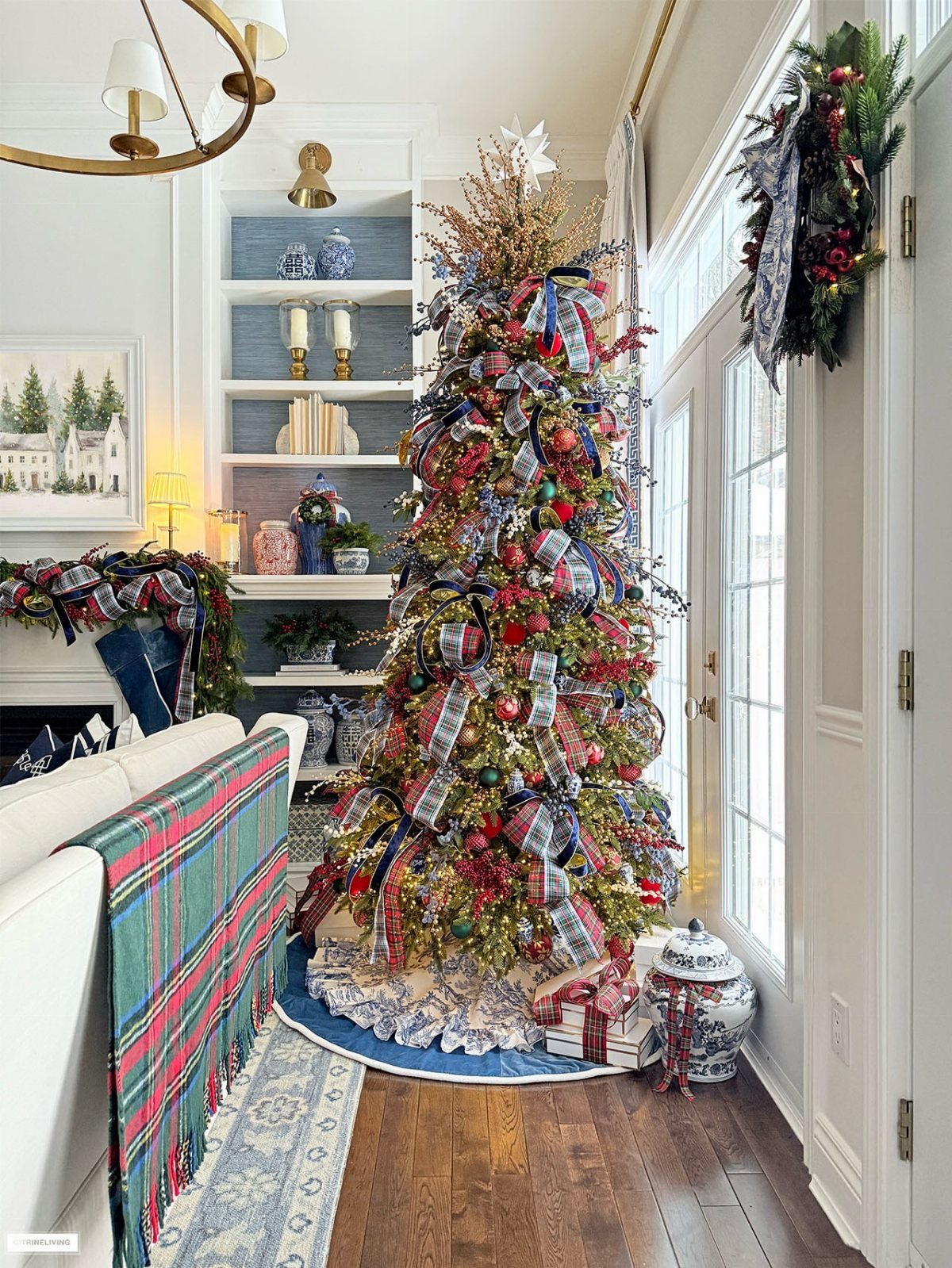 11 Christmas Tree Decorations with Ribbon Ideas 8 Decorated Christmas tree with red ornaments and blue plaid ribbons in a bright room