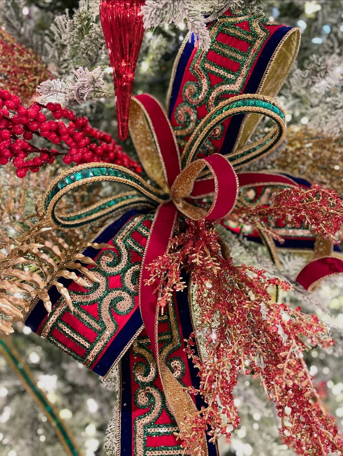 11 Christmas Tree Decorations with Ribbon Ideas 5 Red, gold, and green ornate ribbons tied in a bow on a Christmas tree.