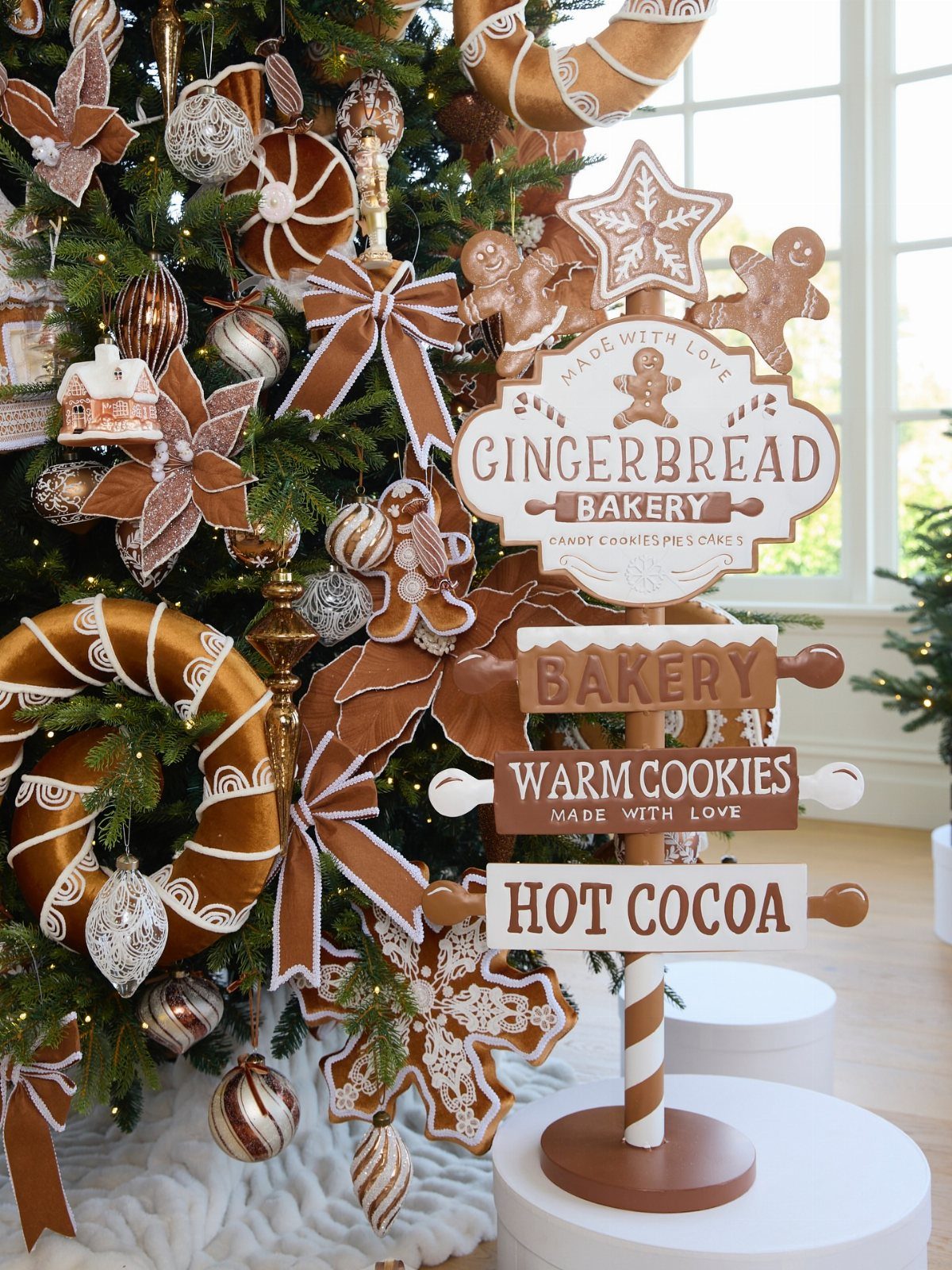 5 Christmas Tree in Kitchen Ideas with Photos 2 Gingerbread-themed Christmas tree with cookie ornaments and a bakery sign in a bright room.