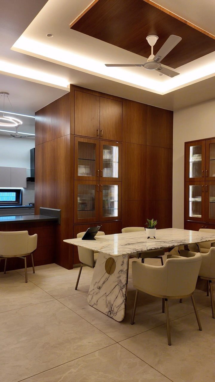 13 Contemporary Dining Room Decor Ideas for 2026 3 Marble dining table and beige chairs under a recessed ceiling with cove lighting.