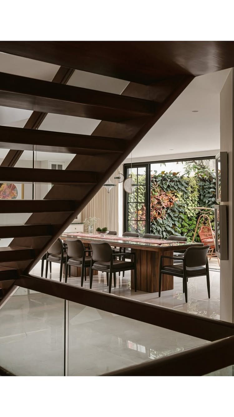 13 Contemporary Dining Room Decor Ideas for 2026 7 Modern dining room with wooden table and black chairs opening to a vertical garden.