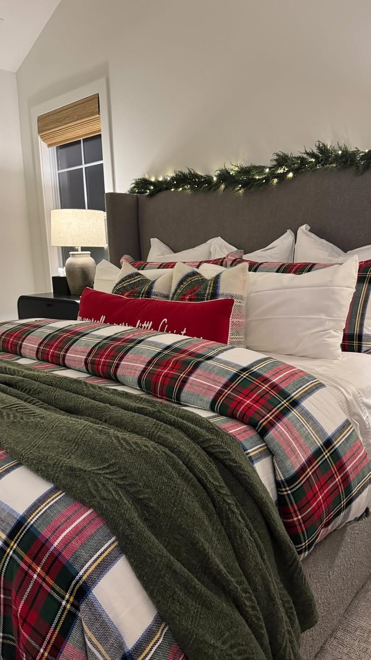 8 Cozy Christmas Bedroom Aesthetic Ideas to Try 7 Bed with red and green plaid linens and festive garland lights on headboard.