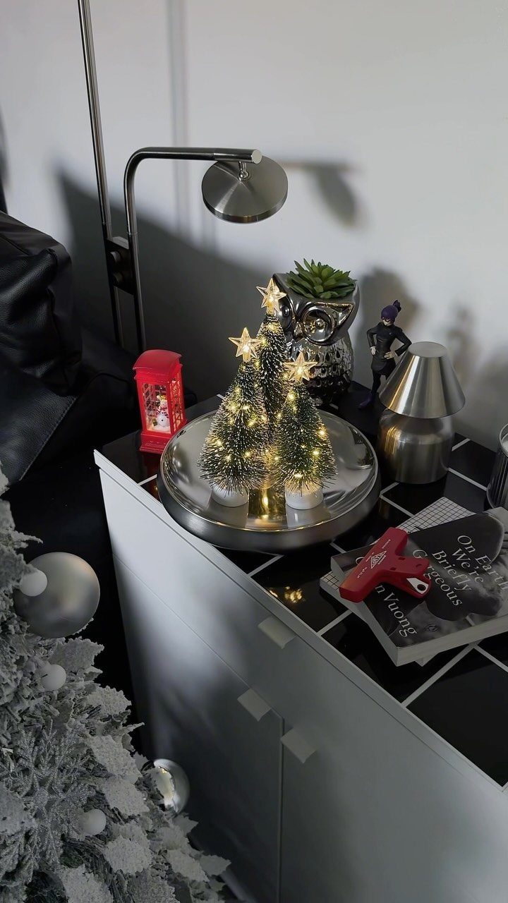 8 Cozy Christmas Bedroom Aesthetic Ideas to Try 2 Three mini lit Christmas trees with gold stars on a silver tray.