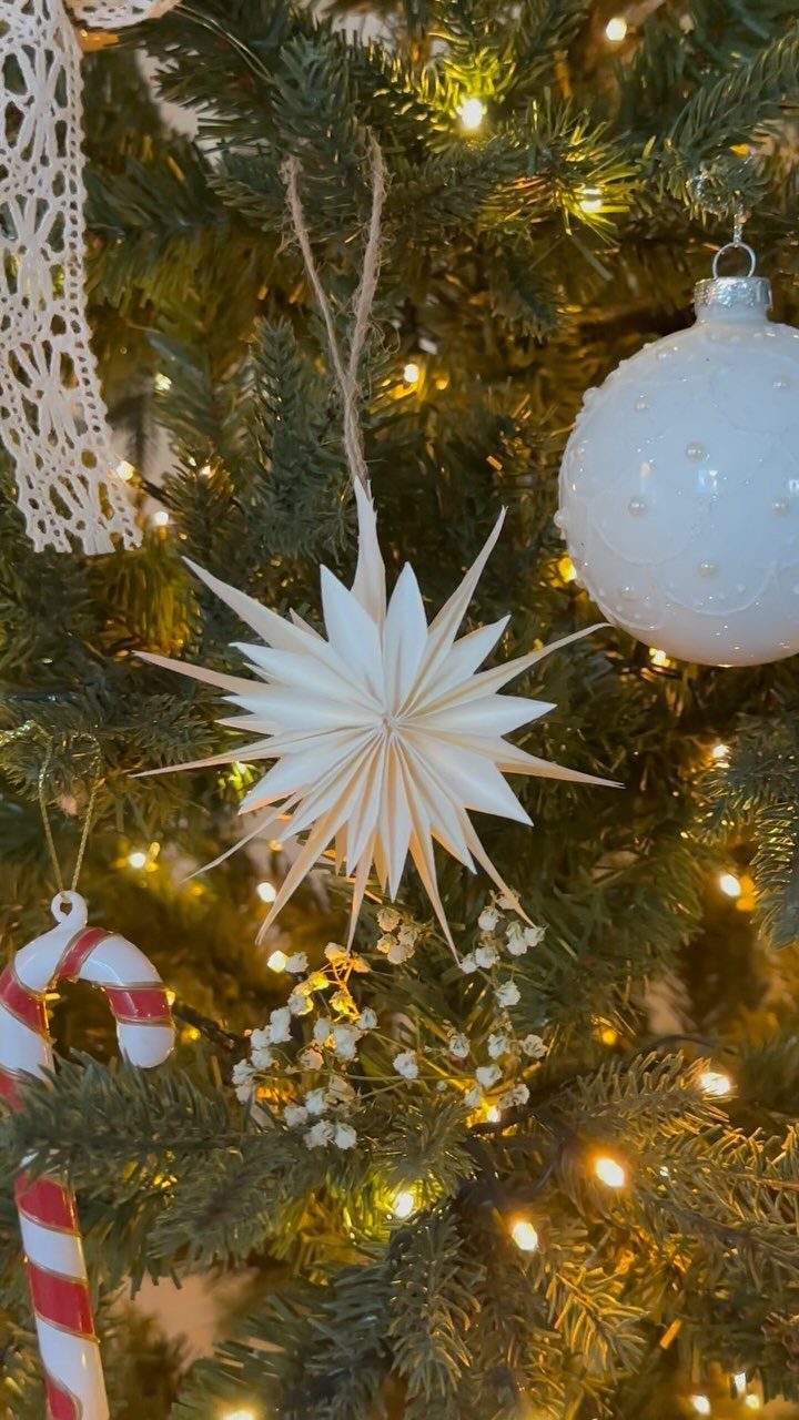 12 Cozy Christmas Living Room Ideas with Photos 5 White paper star ornament hanging on a lit Christmas tree with candy canes.