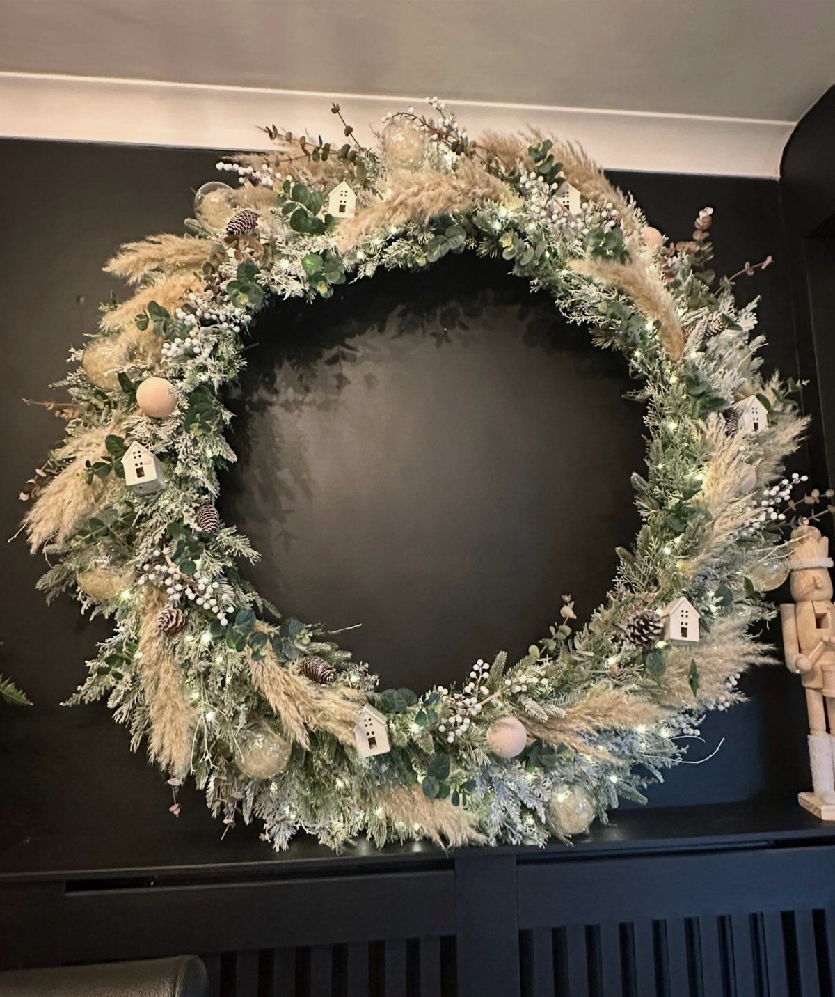 12 Cozy Christmas Living Room Ideas with Photos 4 Large festive wreath with greenery and twinkle lights on a dark wall