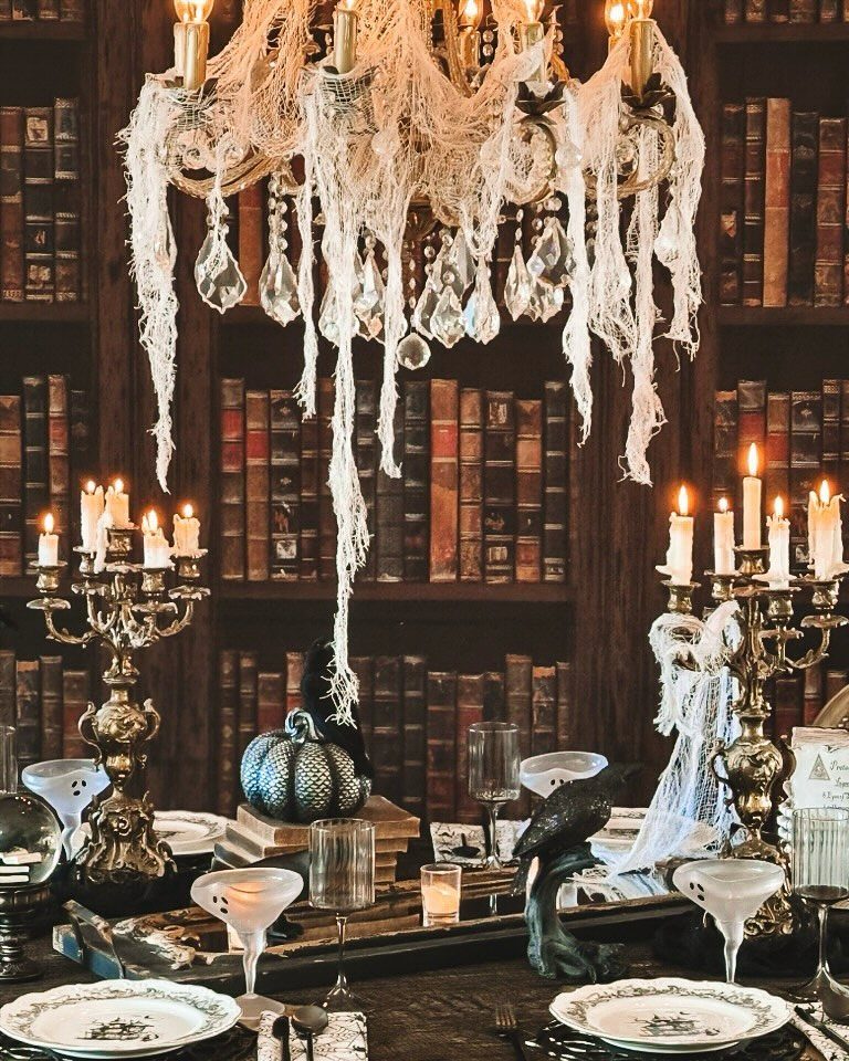 11 Dark Academia Dining Room Ideas for Moody Elegance 9 Dining table with gold candelabras and a tattered chandelier against a library backdrop.