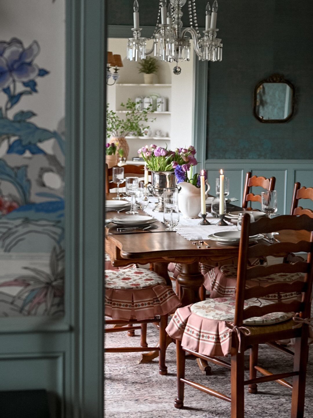 11 Dark Academia Dining Room Ideas for Moody Elegance 6 Dark teal dining room with a wooden table, crystal chandelier, and ruffled chairs.