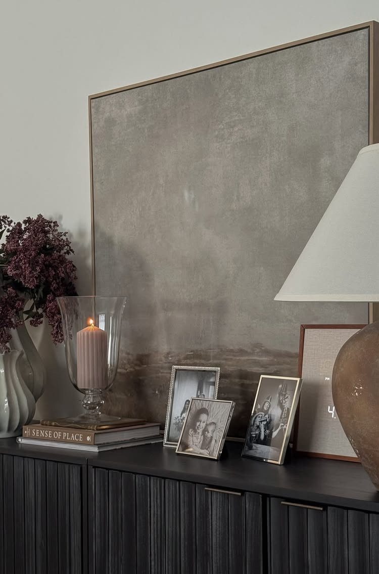 10 Ideas for Decorating a Dining Room Sideboard 5 Dark grey sideboard with closed cabinetry decorated with photos, a candle, and artwork.