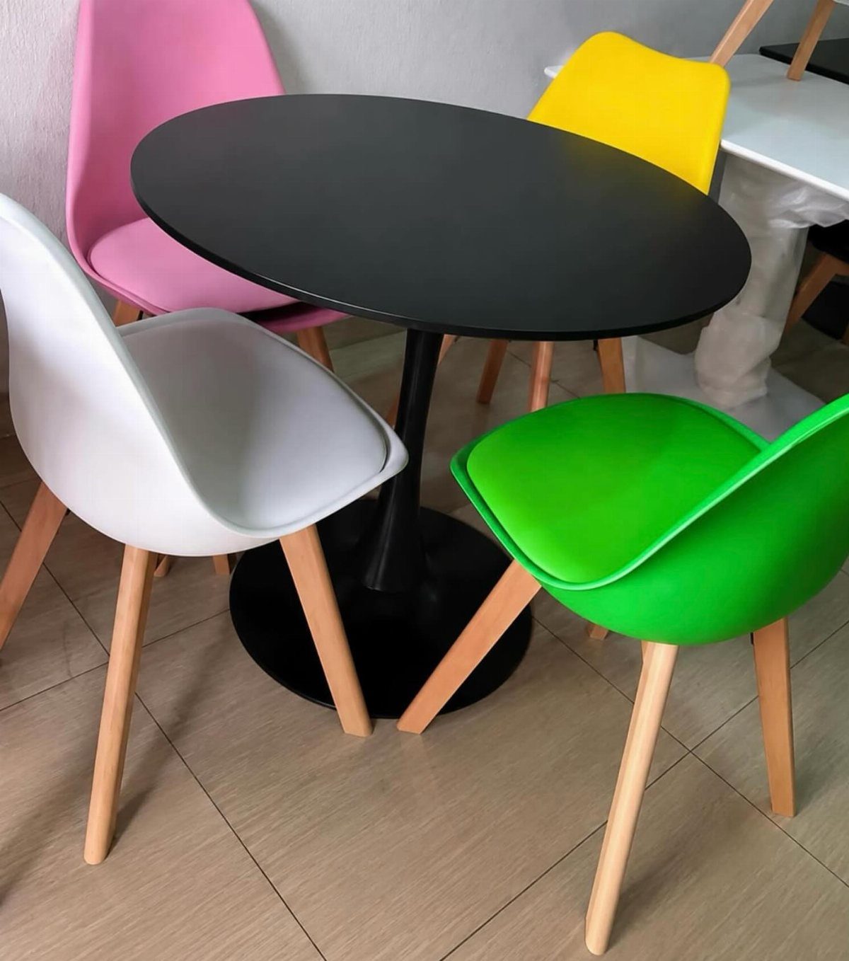 15 Dining Ideas for Small Spaces That Maximize Every Inch 10 Round black table with colorful pink, yellow, green, and white plastic chairs.