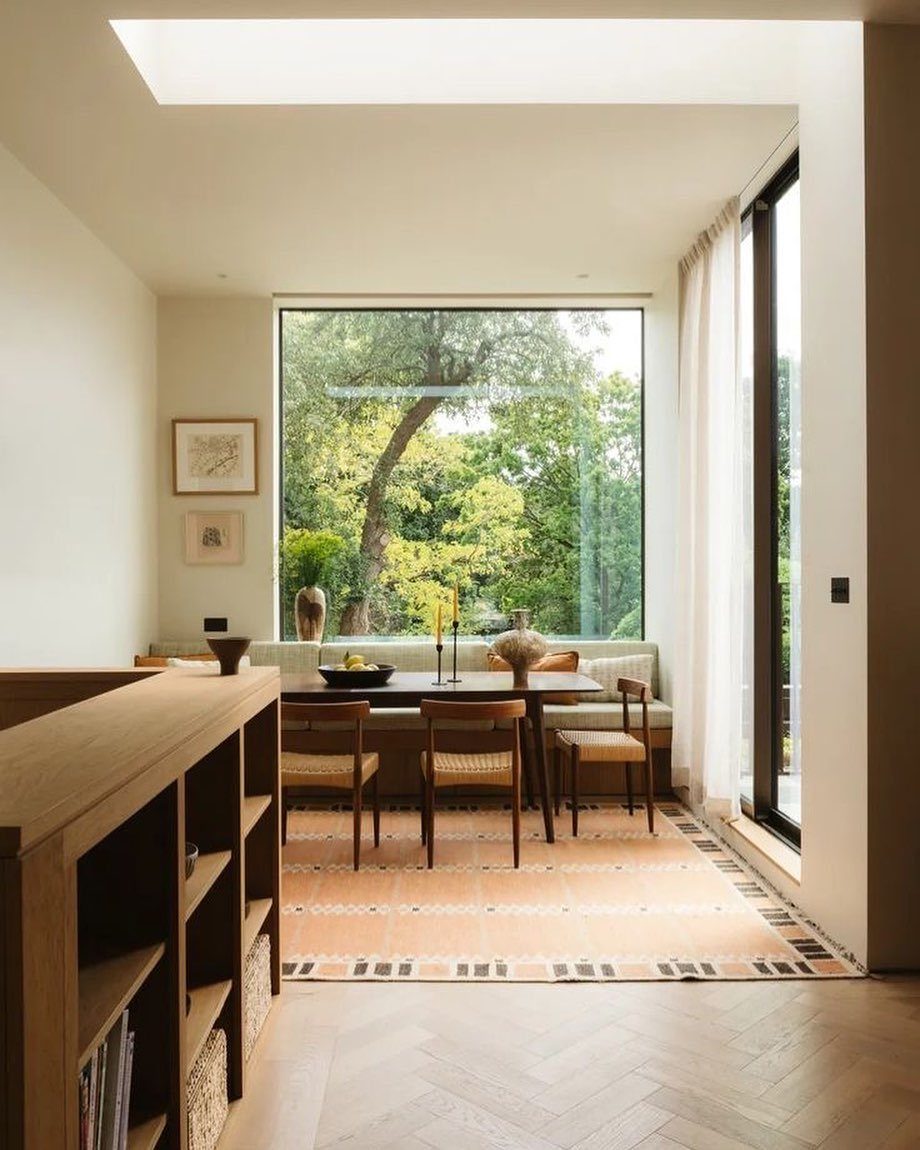 15 Dining Ideas for Small Spaces That Maximize Every Inch 2 Dining table and built-in bench positioned in front of a large window with greenery.