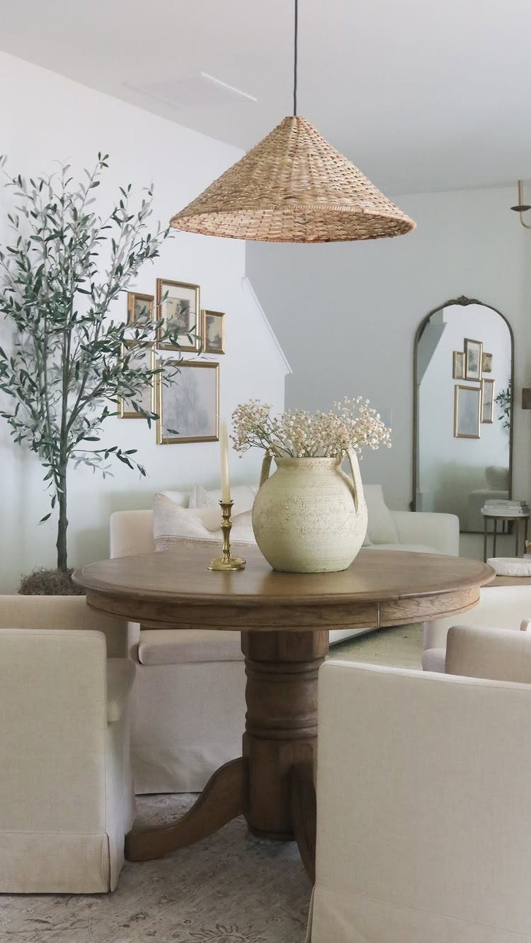 15 Dining Ideas for Small Spaces That Maximize Every Inch 9 Round wooden pedestal table with cream chairs under a woven cone pendant light.