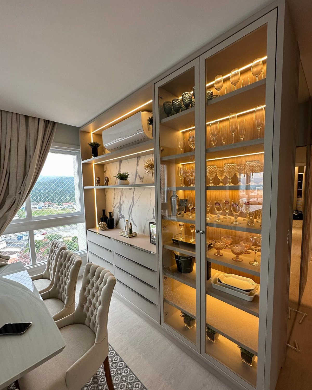 Modern dining room buffet with a glass cabinet and illuminated shelves for glassware.