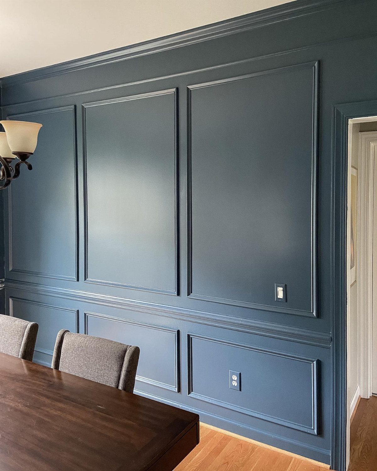 6 Dining Room Chair Rail Ideas for a Polished Look 3 Deep blue dining room wall with symmetrical picture frame molding and chair rail.