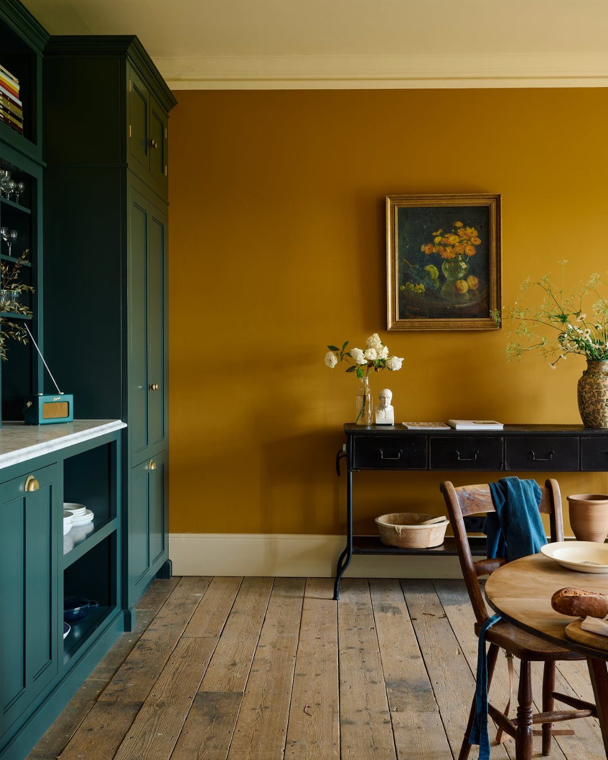 9 Dining Room Color Ideas for a Welcoming Space 6 Deep yellow wall in a dining room with teal cabinetry and rustic wood floors.