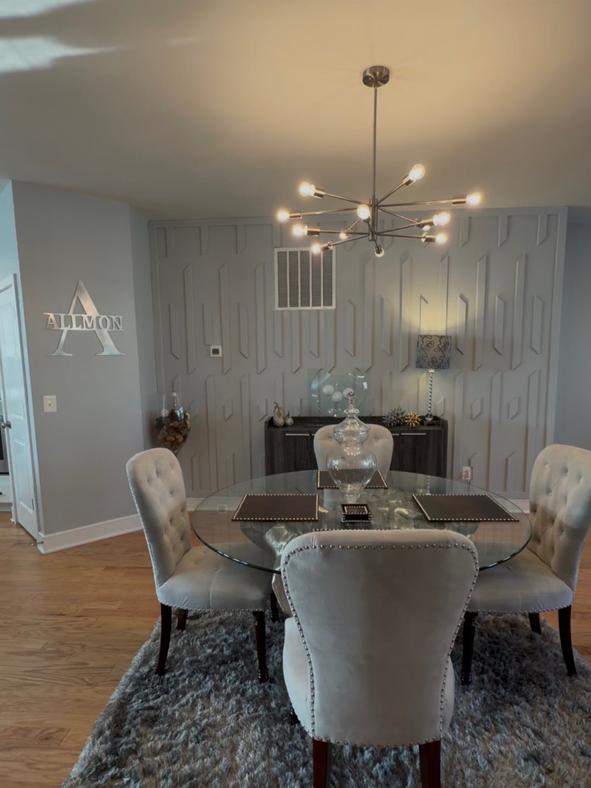 9 Dining Room Color Ideas for a Welcoming Space 3 Gray dining room with a glass table, upholstered chairs, and a modern chandelier.