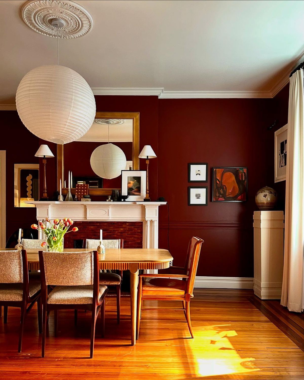 9 Dining Room Color Ideas for a Welcoming Space 9 Dining room with deep terracotta red walls, wooden furniture, and a white paper lantern.