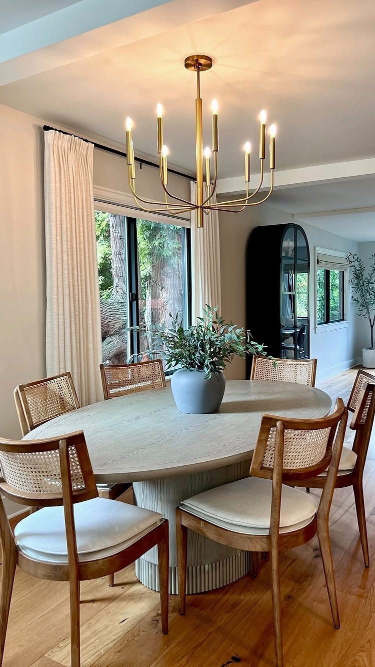 15 Dining Room Decor Modern Ideas with Style and Function 4 Gold multi-arm chandelier hanging over an oval dining table with cane-back chairs.
