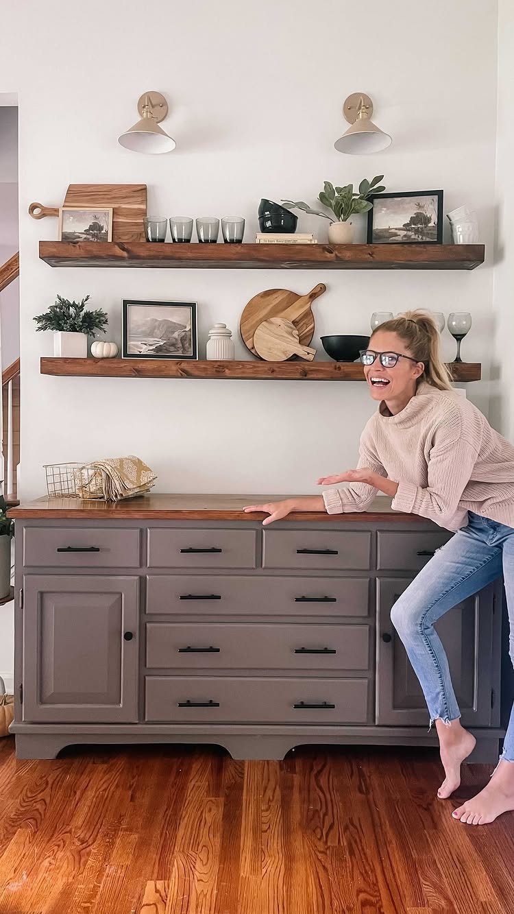 15 Dining Room Decor Modern Ideas with Style and Function 10 Woman leaning on grey sideboard with wooden floating shelves on white wall
