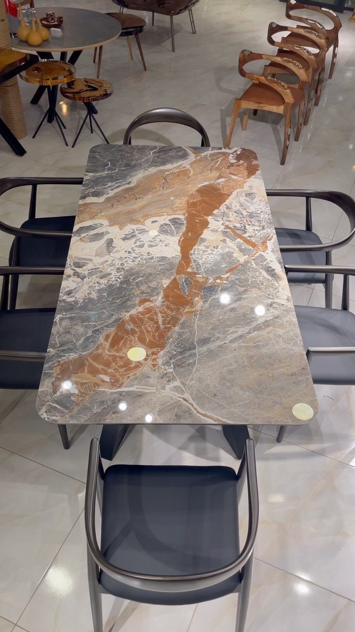 10 Dining Room Decorating Ideas for 2027 That Feel Fresh 7 Marbled stone dining table with grey curved chairs in a modern showroom setting.