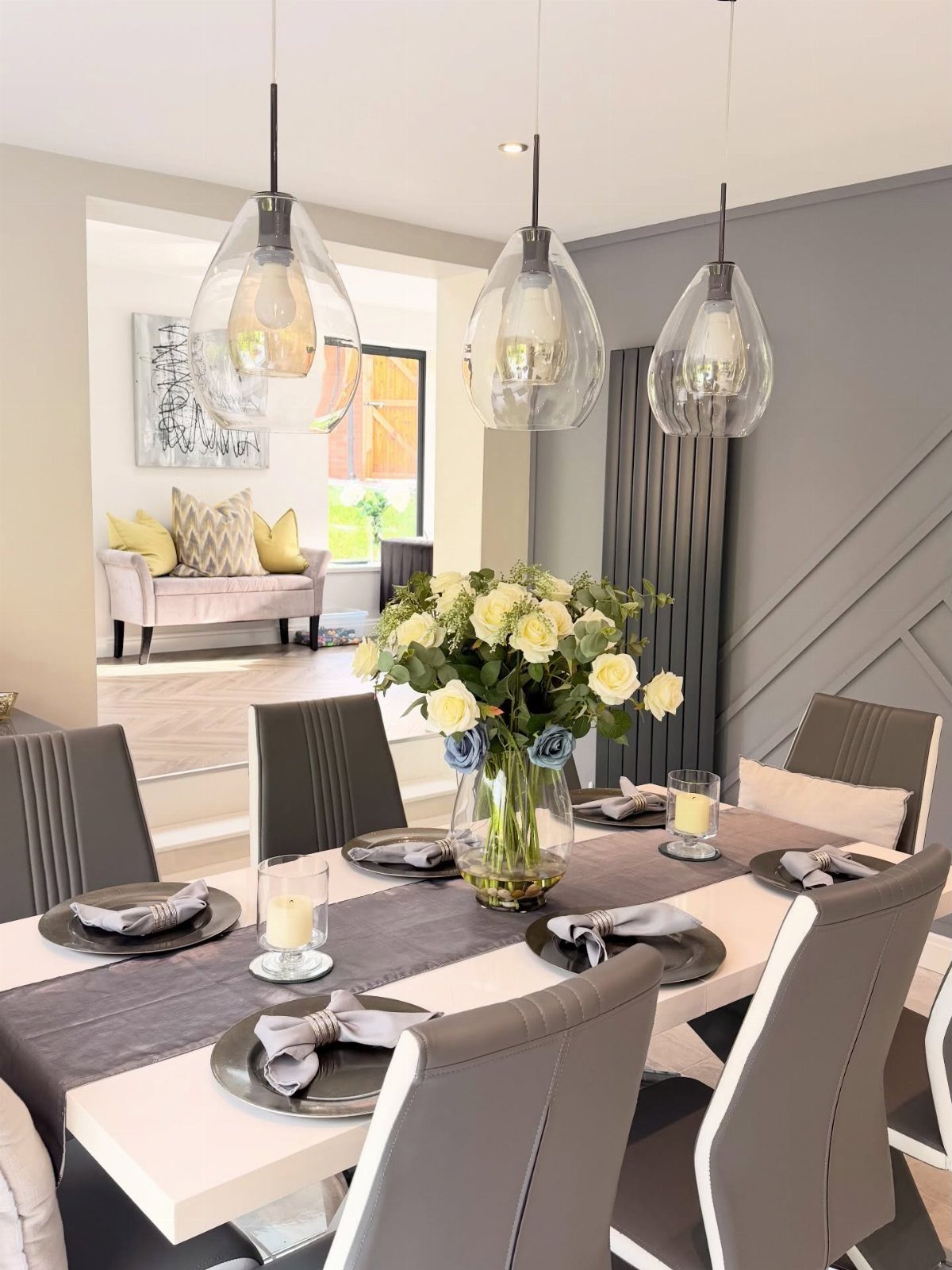 10 Dining Room Grey Wall Ideas for a Refined Look 4 Dining room with grey paneled walls, white table, and glass pendant lights.