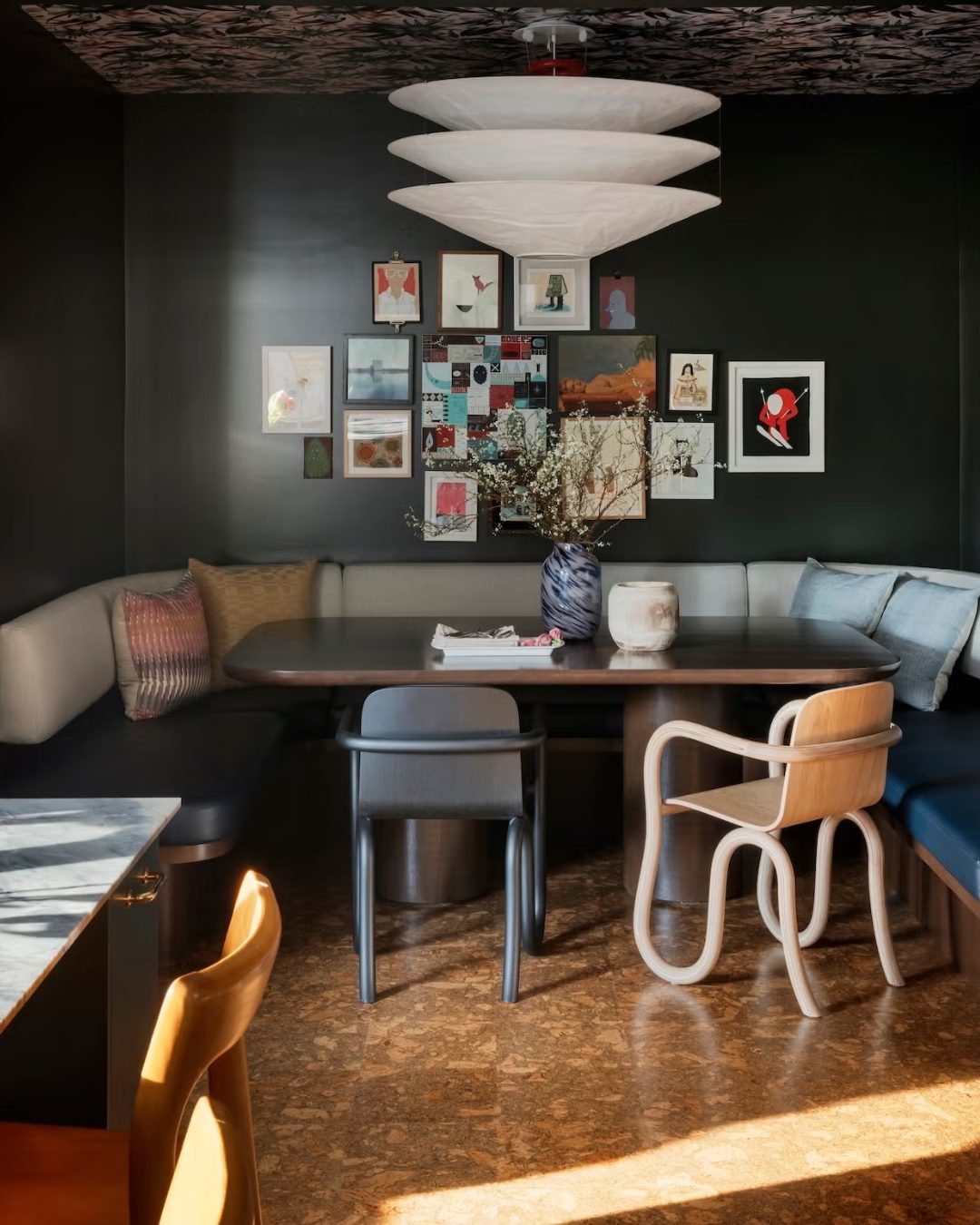 Dining room table with mismatched grey and wooden chairs and a built-in banquette.