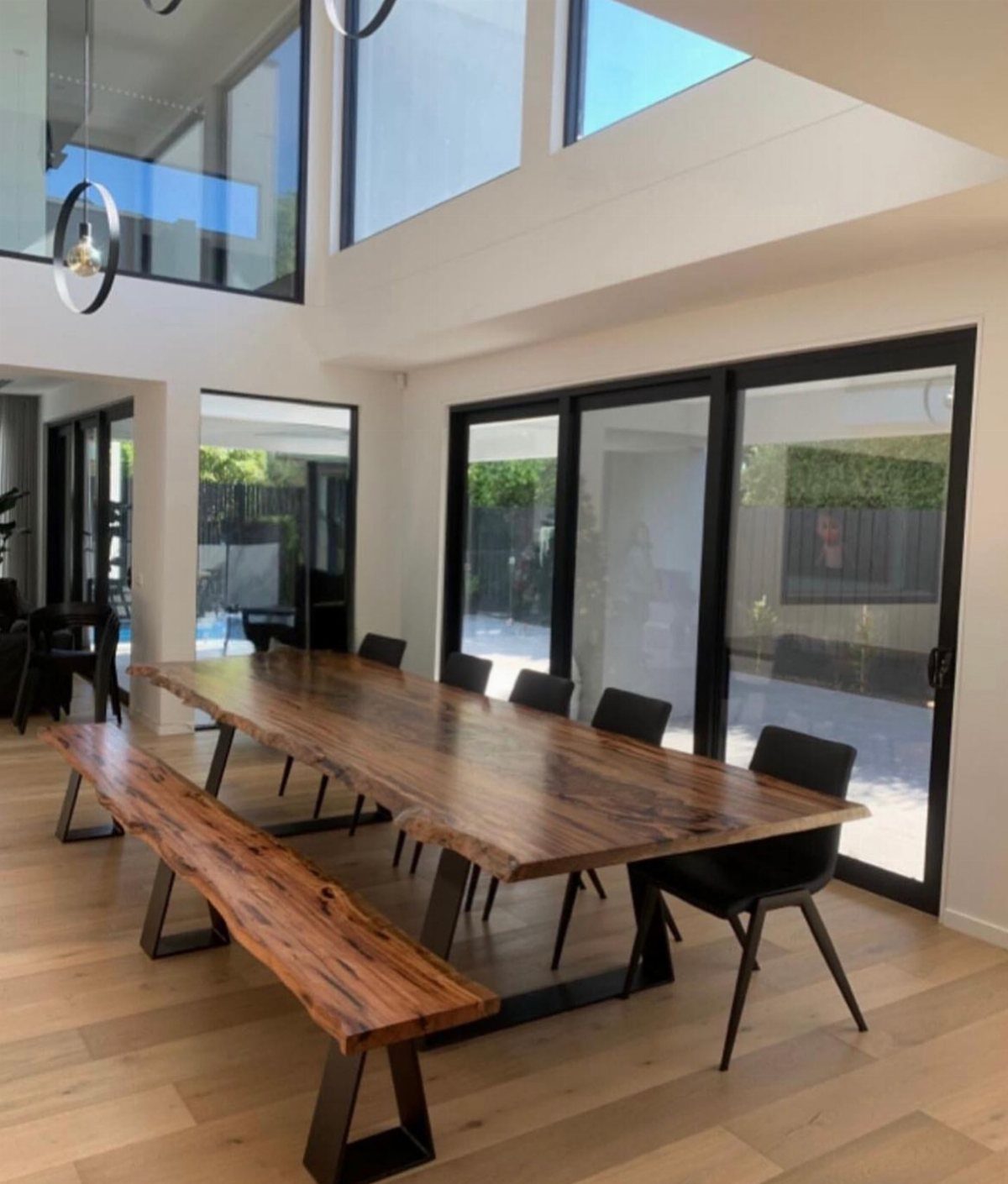 Dining Room Table for 12: 3 Handcrafted Options 3 Live edge wooden dining table with metal base, matching bench, and black chairs.