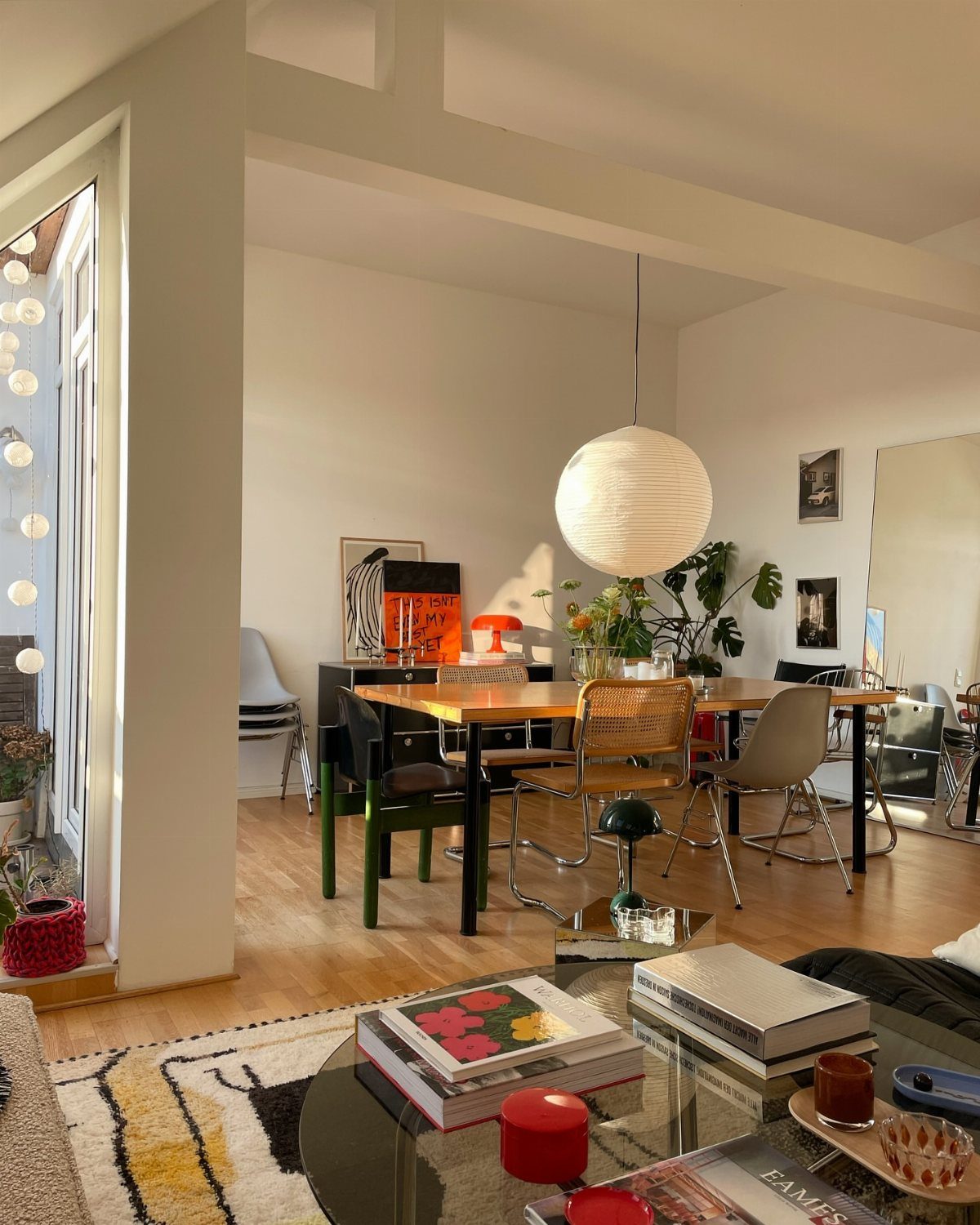 7 Dining Room Table Ideas for a Standout Space 4 Rectangular wooden dining table with mixed chairs and a large spherical pendant light.