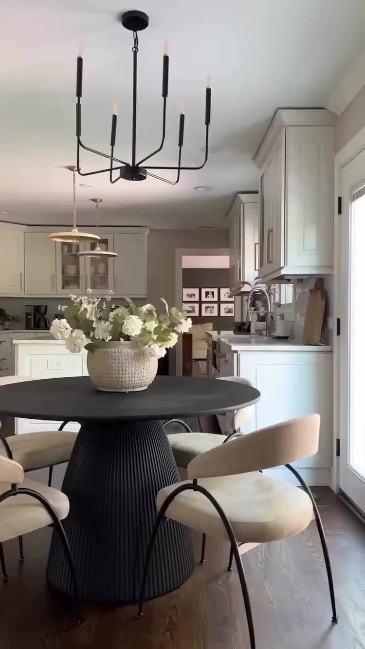 7 Dining Room Table Ideas for a Standout Space 3 Round black dining table with a ribbed pedestal base and cream upholstered chairs.