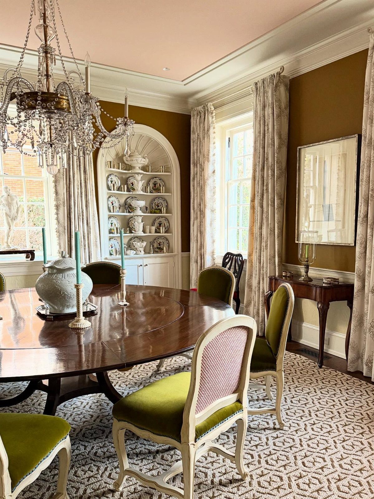 11 Dining Room Tray Ceiling Ideas with Photos 11 Formal dining room with pink ceiling, crystal chandelier, and green upholstered chairs.