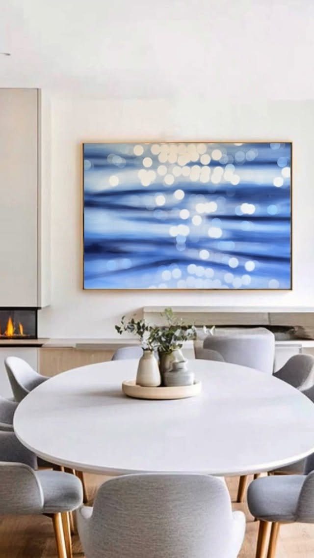 Blue and white abstract painting hanging above a round white dining table