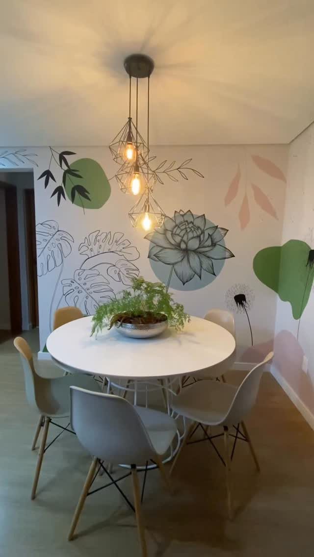 Botanical wall murals of leaves and flowers behind a white dining table and chairs