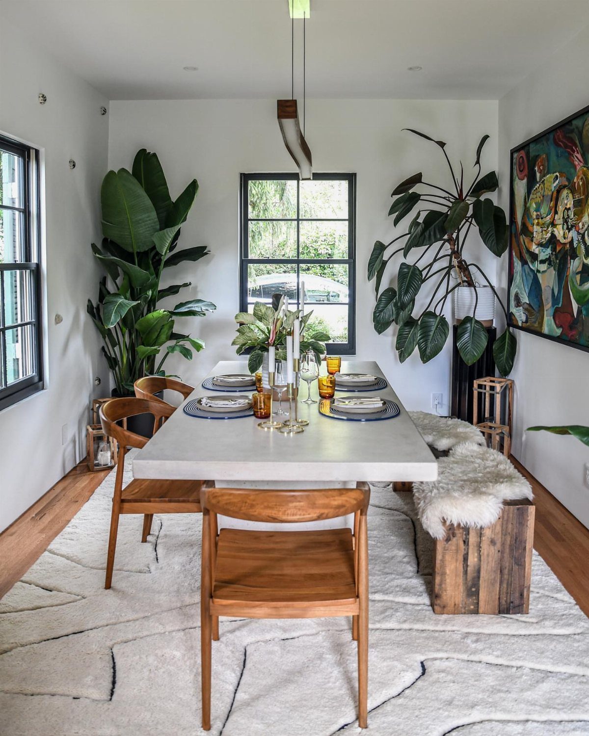Large green potted plants flanking a white dining table in a bright room