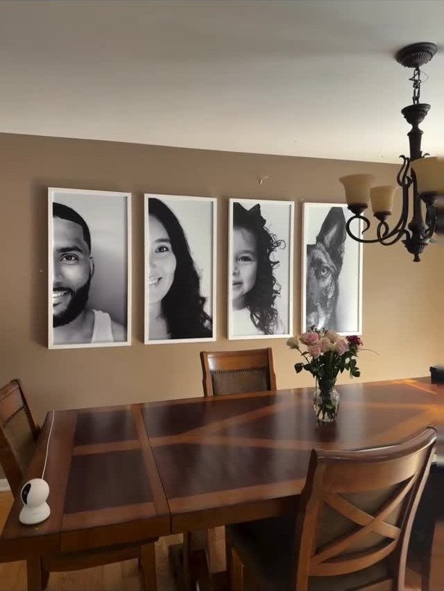 Four black and white family portraits in white frames on a dining room wall
