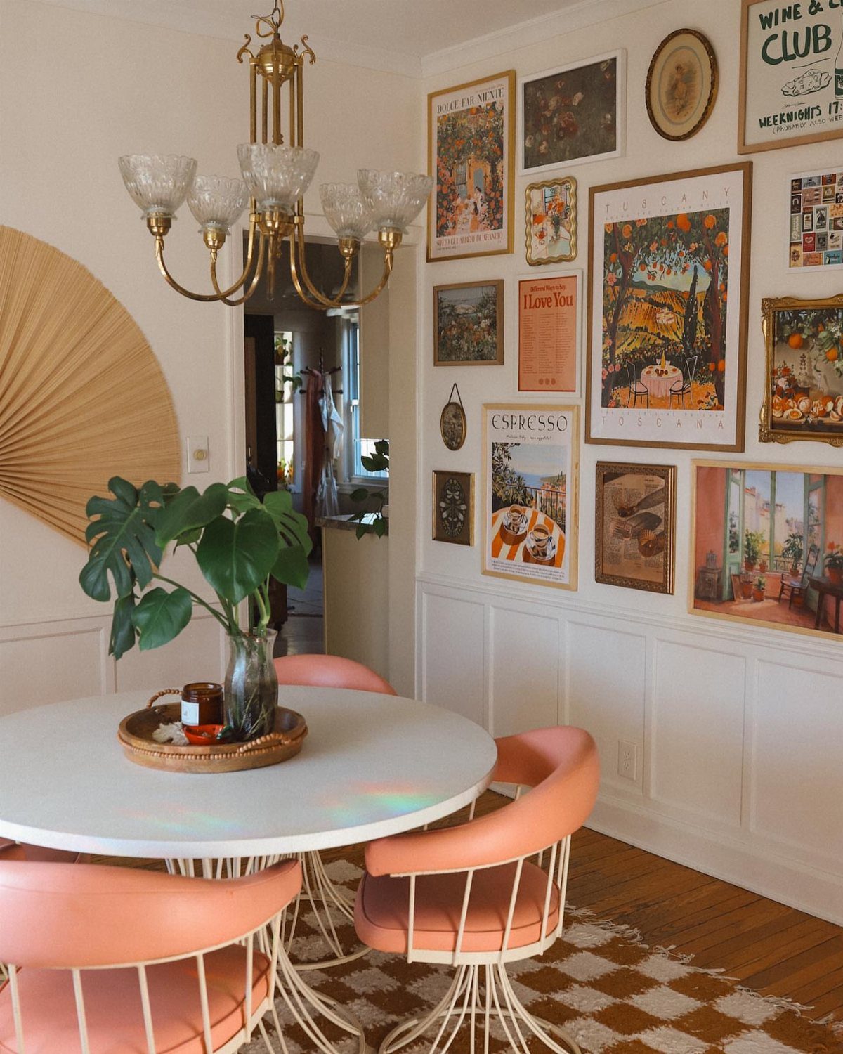 Gallery wall with various framed art pieces above a white dining table and chairs.