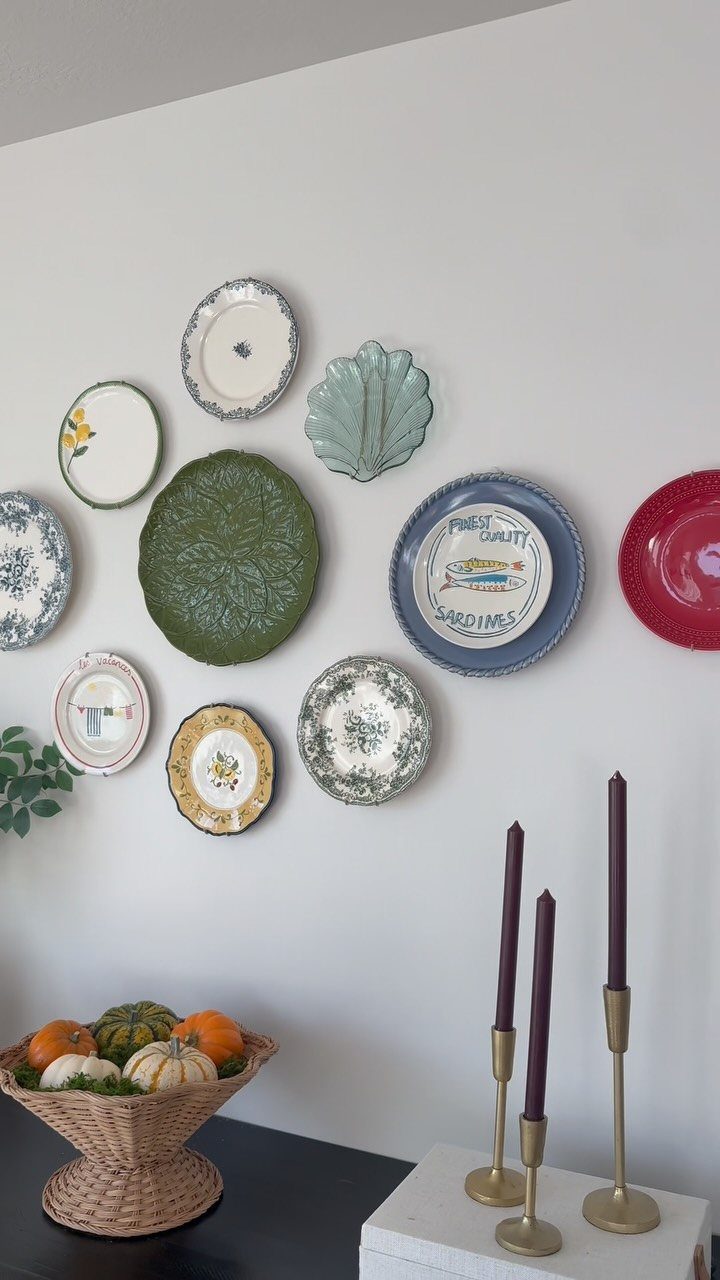 Decorative ceramic plates of various patterns and colors arranged on a grey wall.