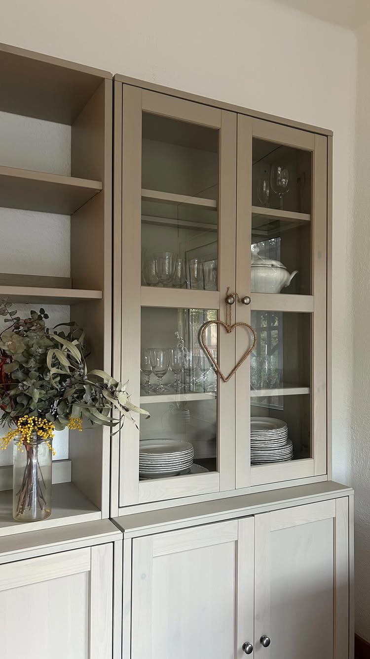 Beige wooden hutch with glass cabinets and open shelving in a dining area