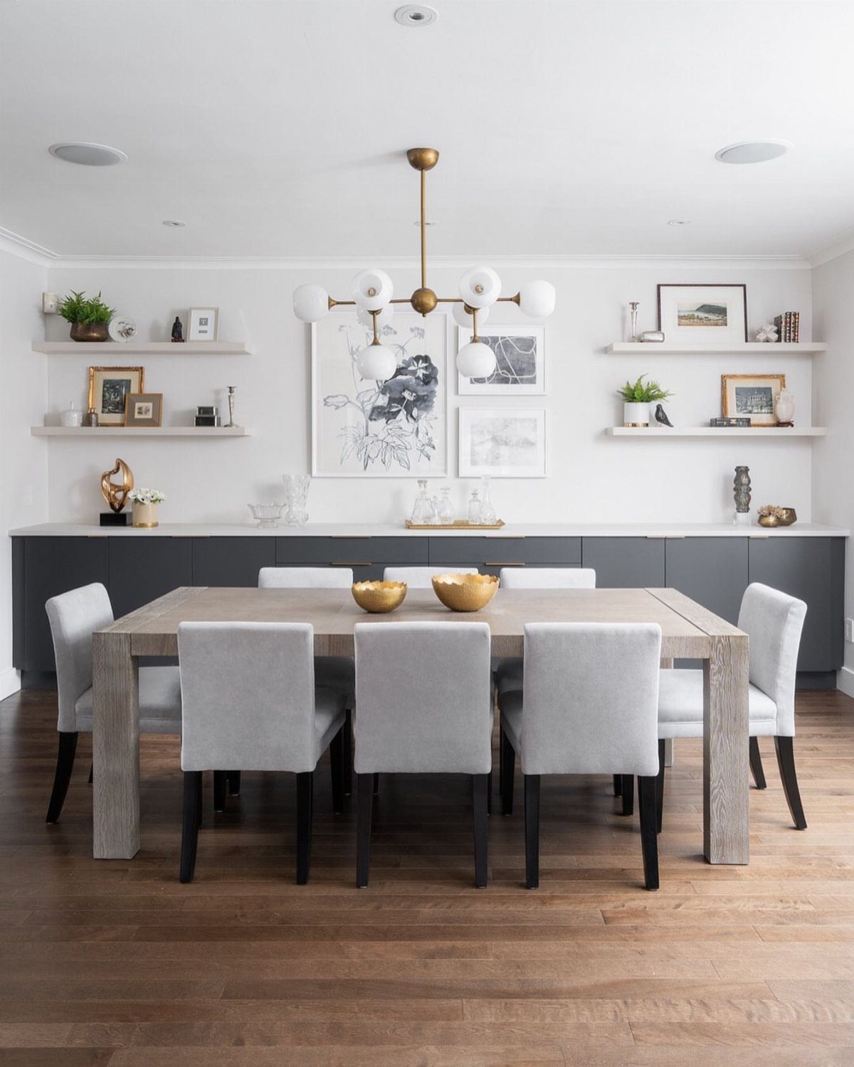 Modern dining room with a wooden table, grey chairs, and a long grey buffet.