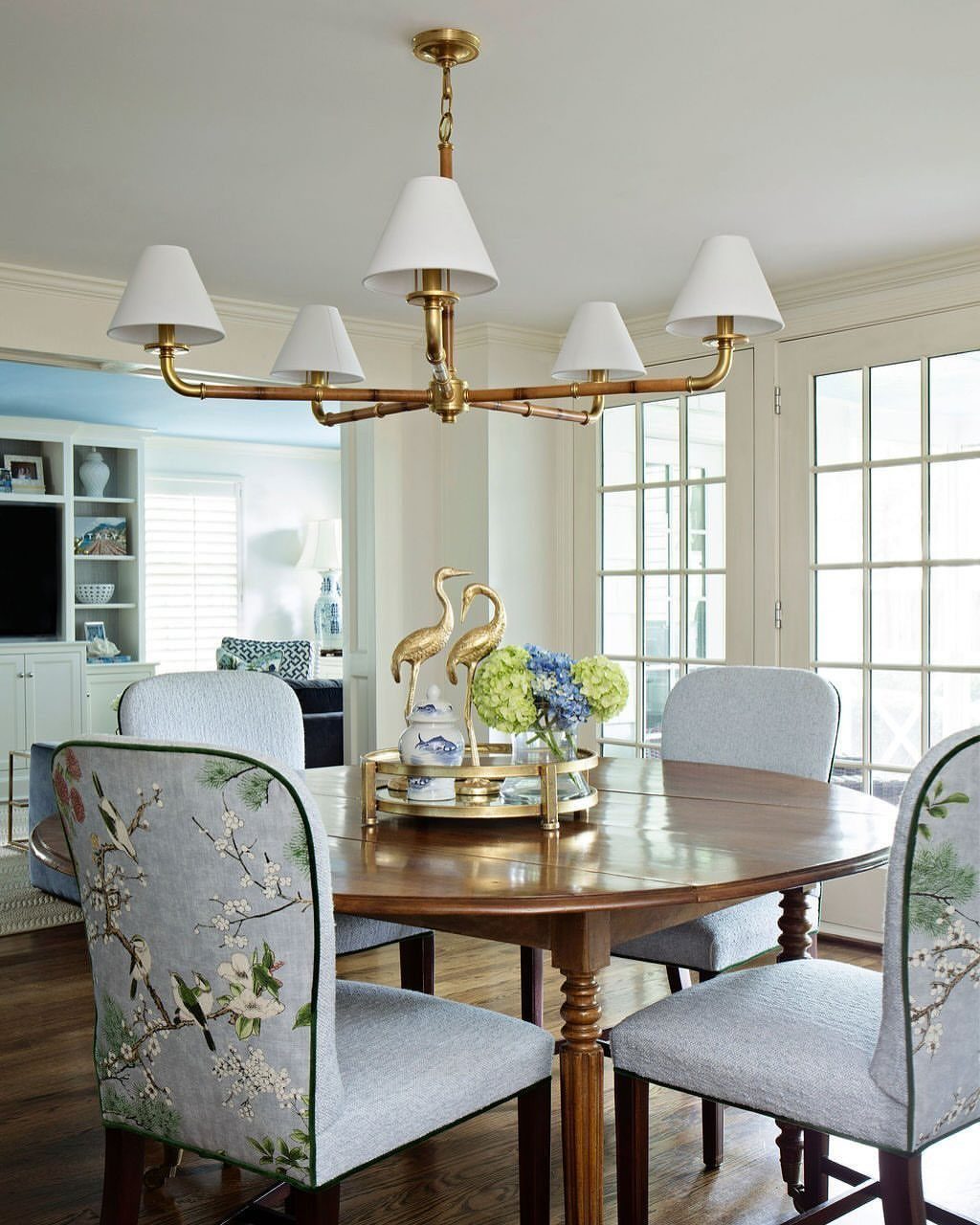 8 Dining Tables for Dark Wood Floors That Work 5 Round wooden dining table with light blue upholstered floral chairs on dark wood floors