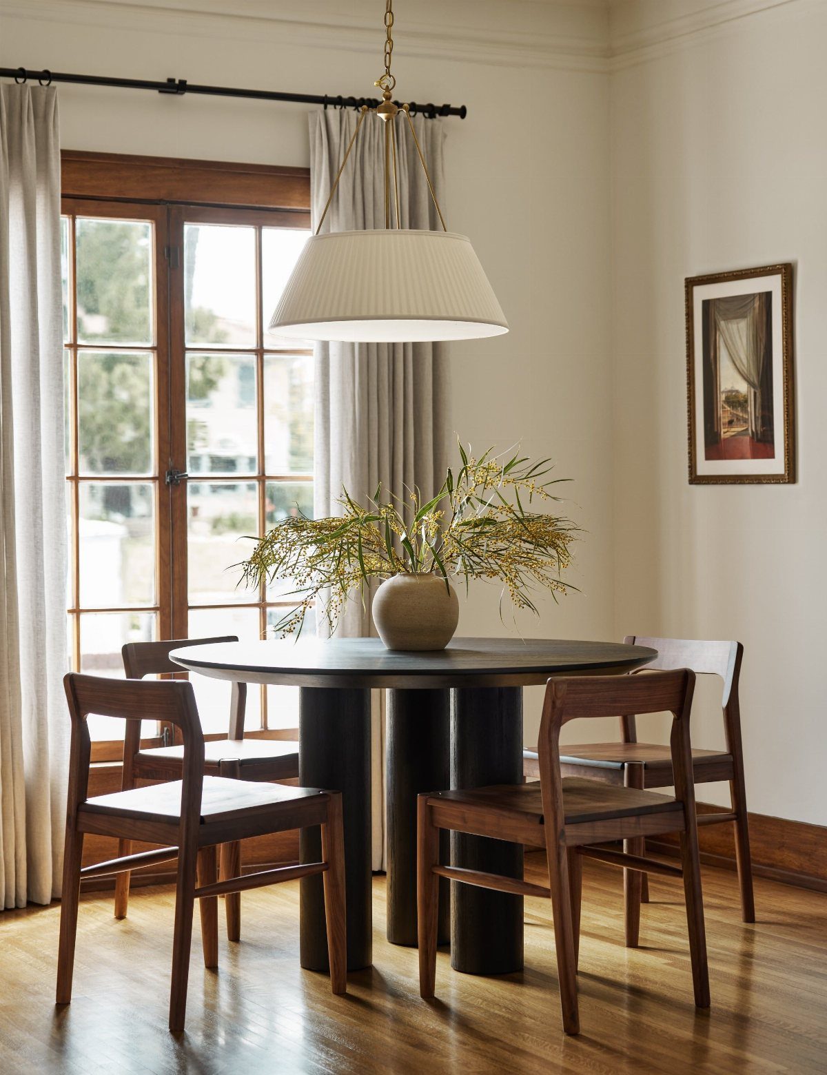 8 Dining Tables for Dark Wood Floors That Work 6 Round black dining table with wooden chairs on a polished wood floor