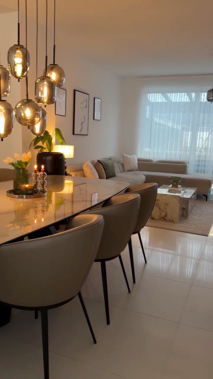 10 Dining Table in Living Room Ideas for Small Spaces 9 Glossy dining table and chairs positioned in a modern living room with a sofa.