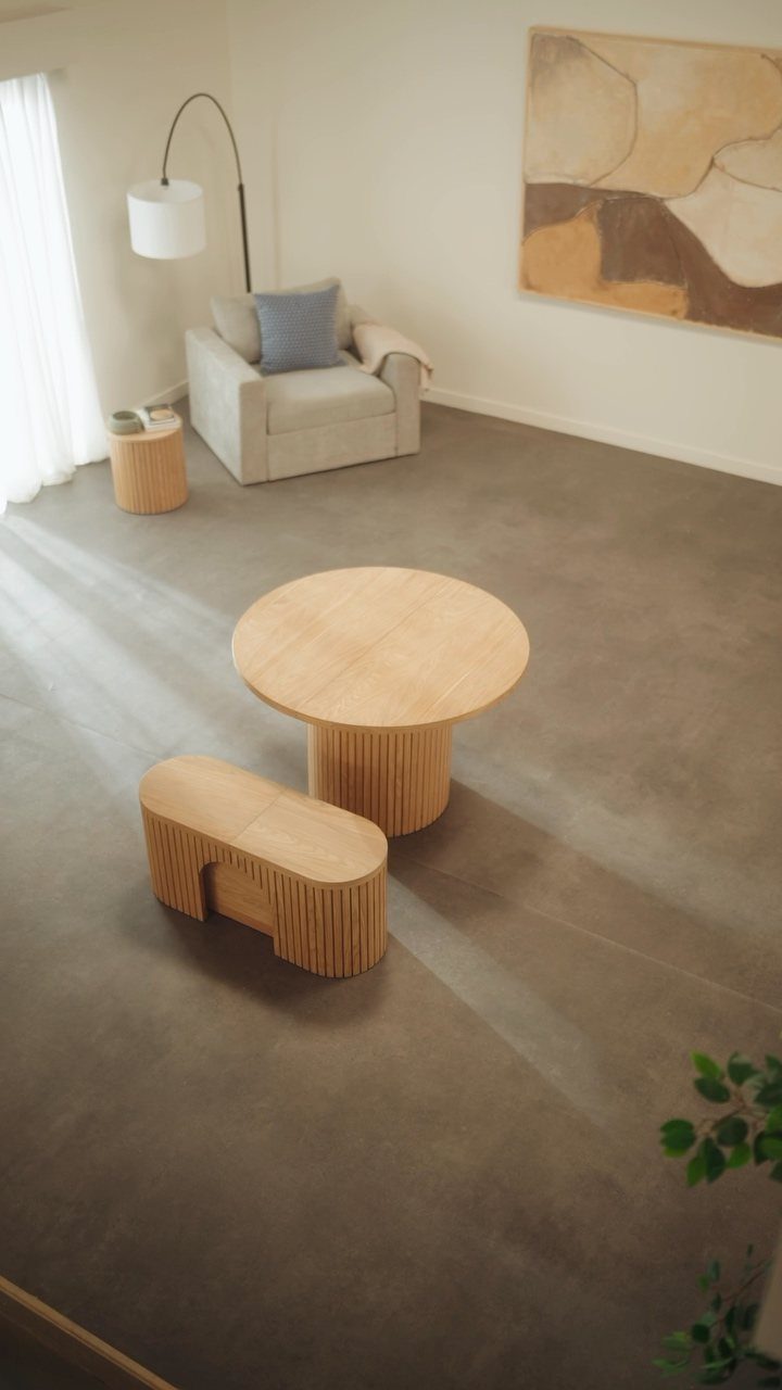 10 Dining Table in Living Room Ideas for Small Spaces 8 Round wooden dining table and bench in a living room with a beige armchair.