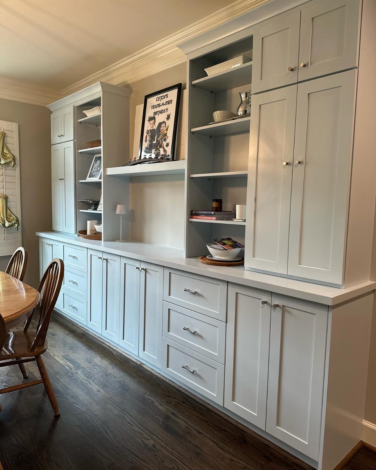 11 Dining Table Ideas for Small Spaces That Maximize Room 11 Light grey built-in shelving and cabinetry unit along a wall in a dining room.