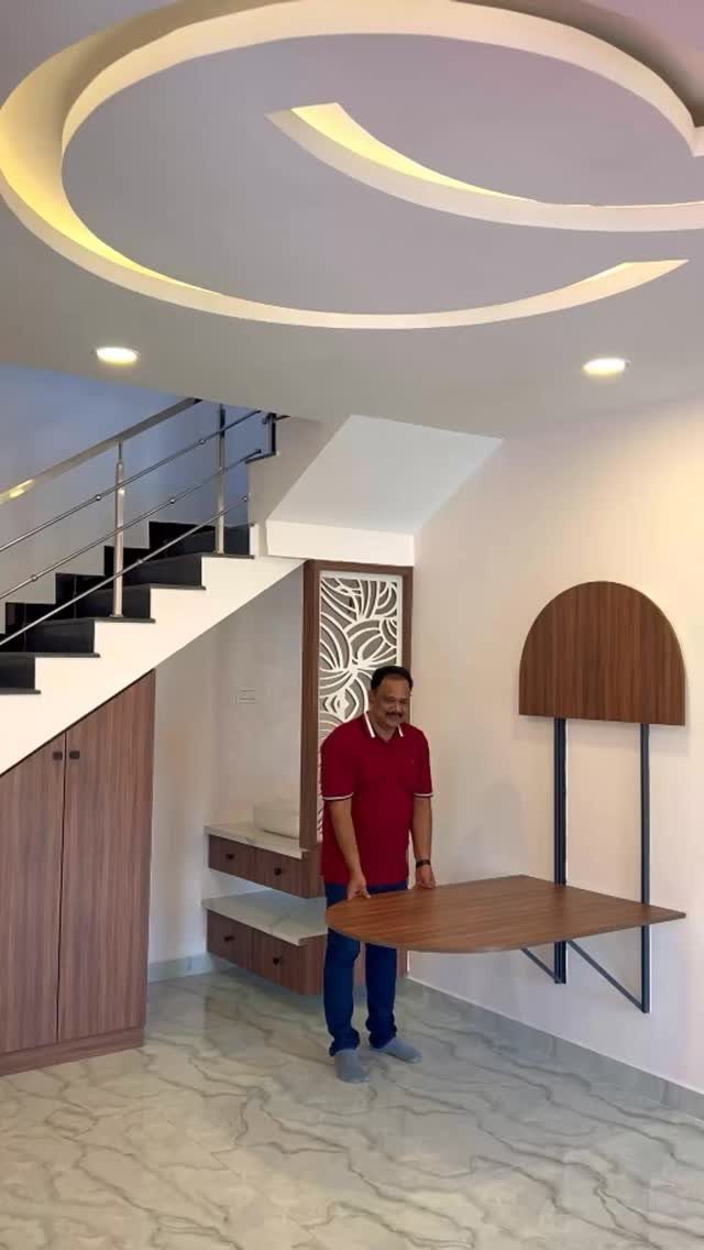 11 Dining Table Ideas for Small Spaces That Maximize Room 3 Wall-mounted folding wooden table in a modern home interior with a man standing nearby.