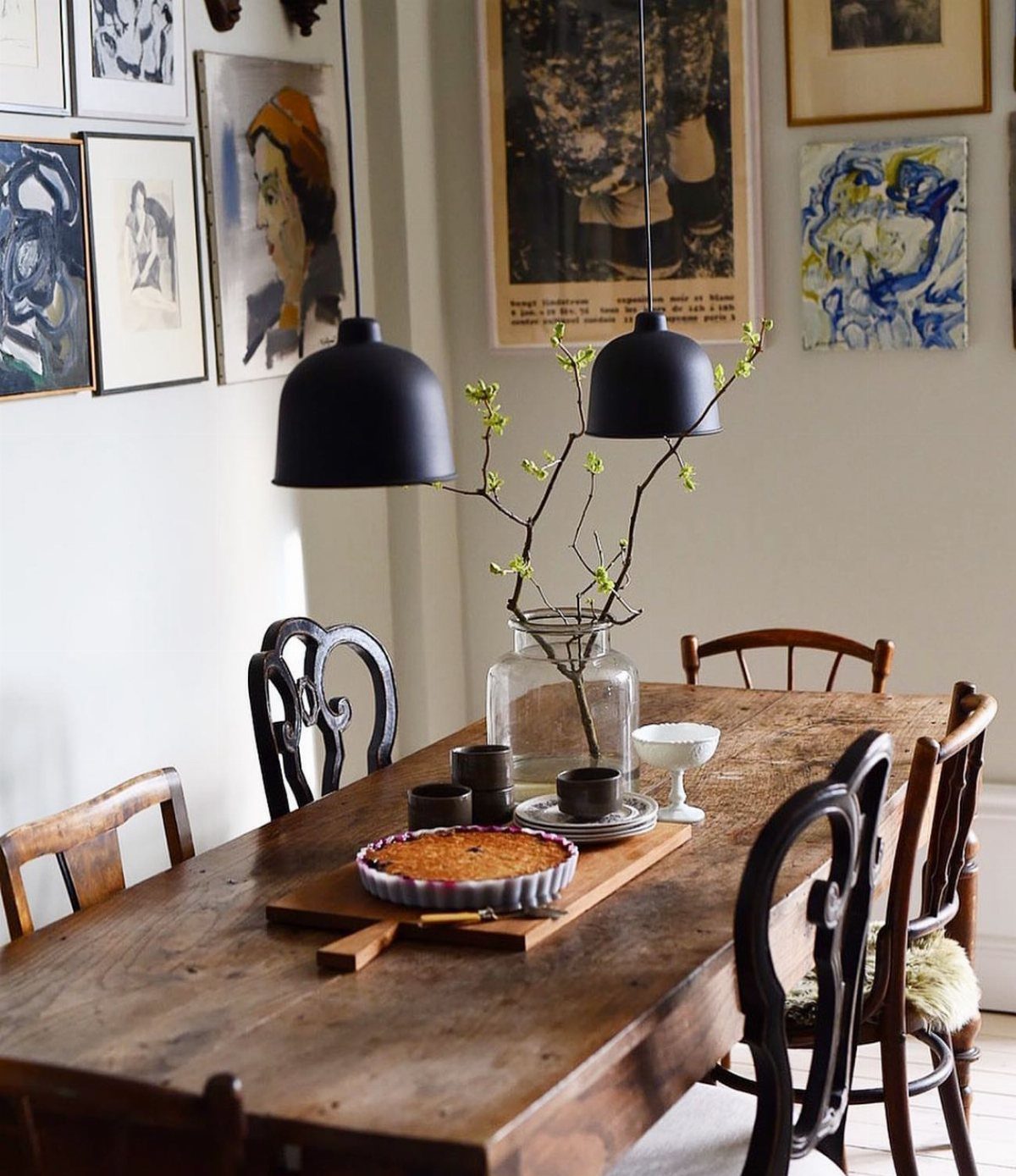 7 Dining Table with Mismatched Chairs Ideas That Work 3 Wooden dining table with mismatched black and brown chairs and wall art.