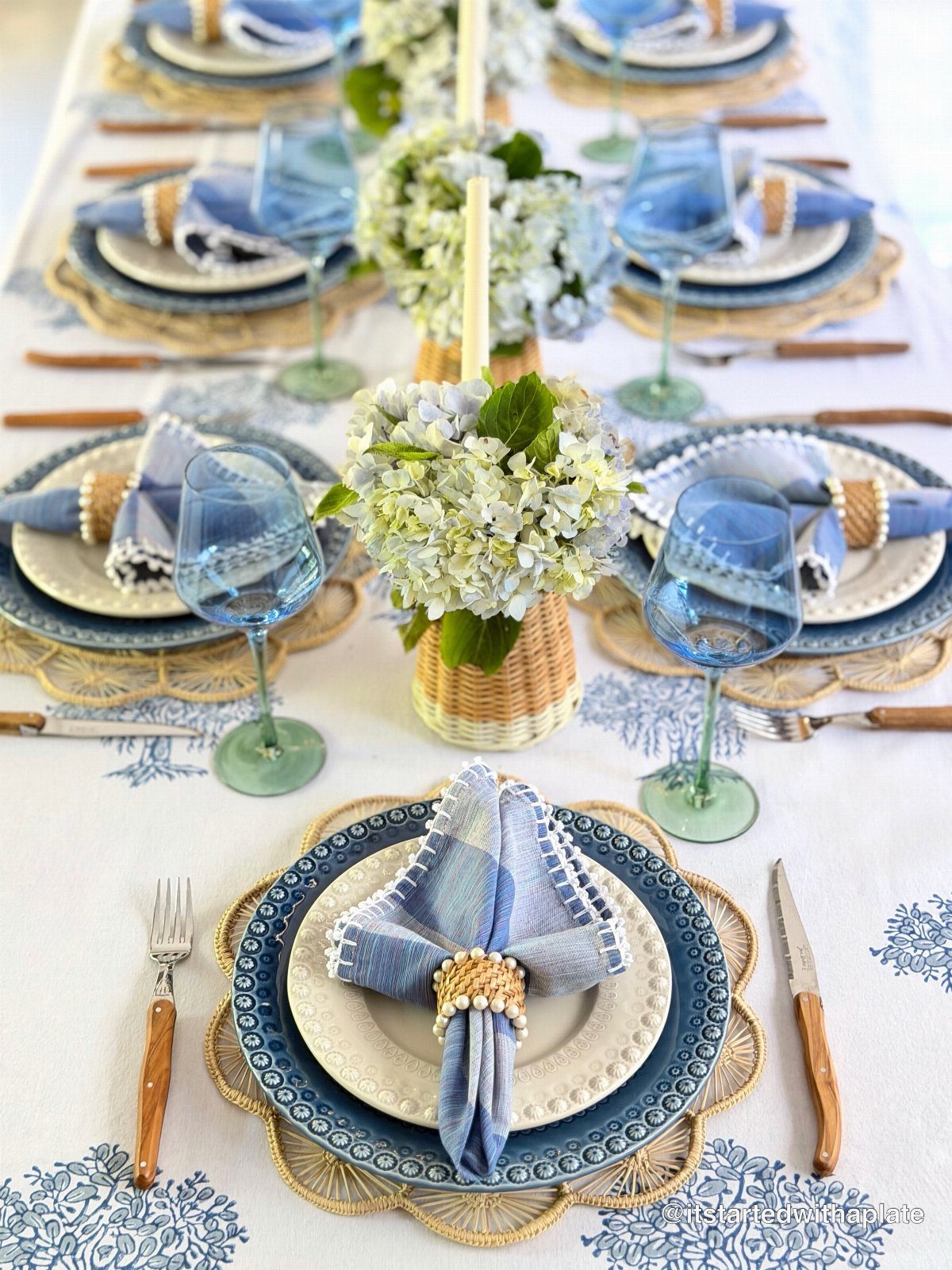 Blue and white dining table setting with floral centerpieces and beaded napkin rings