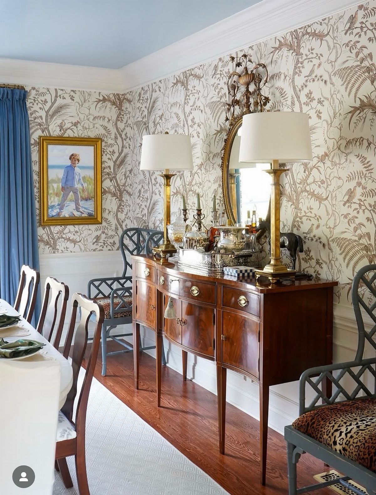 Wooden sideboard with gold lamps and silverware next to a set dining table